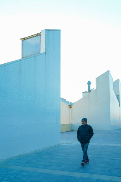 istock Man walking among white buildings 1148406051