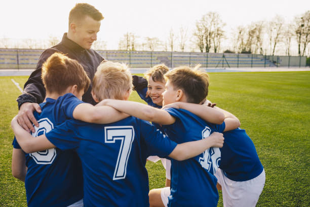 Group Of Children In Soccer Team Celebrating With Coach Group Of Children In Soccer Team Celebrating With Coach team sport stock pictures, royalty-free photos & images