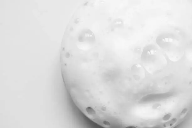Photo of White foam texture from soap, shampoo or cleanser on white background. Clouse up, macro
