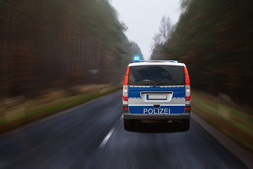 German police car with flashing blue lights in action on a road