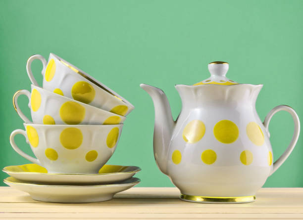 istock Ceramic teapot, a stack of cups in polka dots on a wooden table isolated on a blue pastel background. Copy space 1148424114
