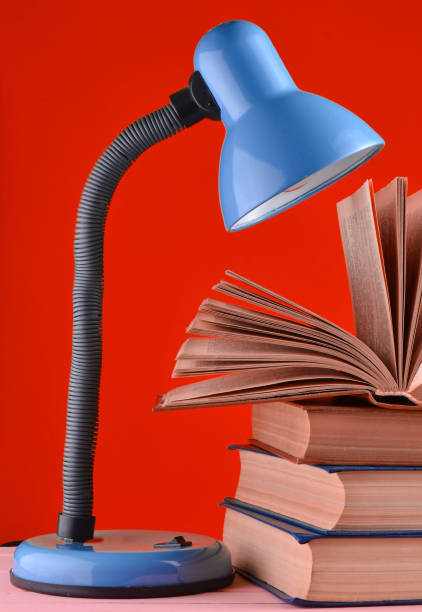istock A table lamp and a stack of books on a table isolated against red wall background 1148424201
