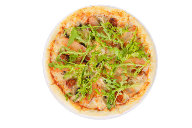 Pizza with arugula, dried tomatoes and mushrooms whole round, cut into pieces, on a white isolated background, view from above