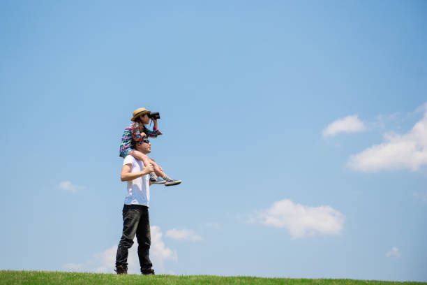 Father and daughter looking afar with binoculars