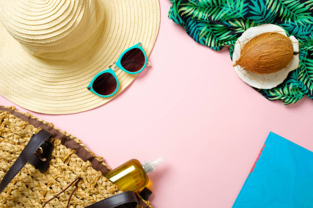istock Women's beach accessories: straw hat, sunglasses, coconut, paper notebook, beach bag with essential oil on pink background. Traveler stuff concept, summer background. Flat lay composition, top view. 1148435947