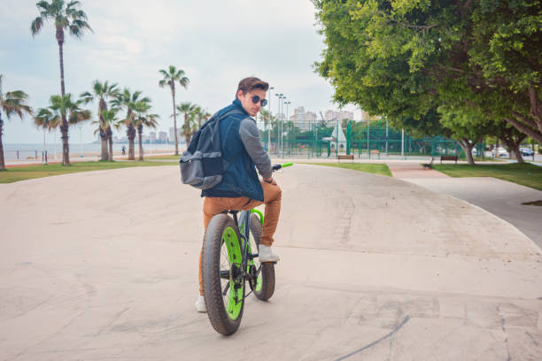 istock Young Handsome Man Posing On Bicycle In Park 1148438373