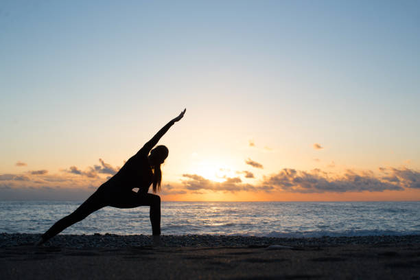 istock Human silhouette doing yoga on the beach at dusk 1148445357