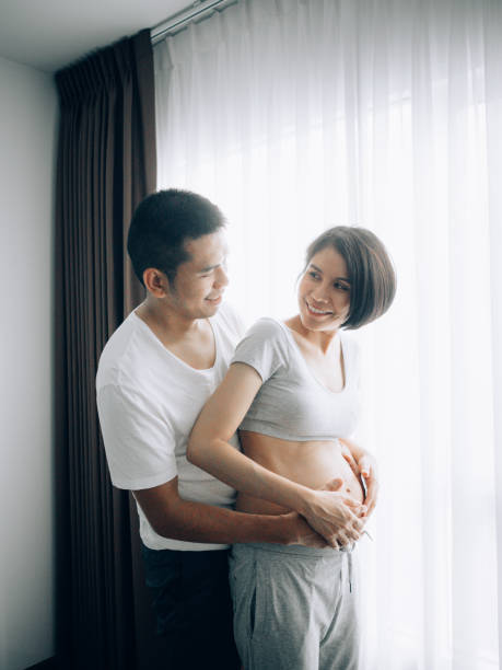 прекрасная пара. наслаждаясь дома готовится к ребенку - human pregnancy rubbing looking down abdomen стоковые фото и изображения