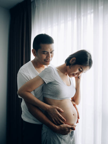 joli couple. appréciant la maison préparant pour le bébé - rubbing human hand togetherness women photos et images de collection