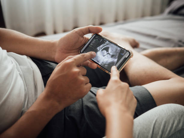 glückliches paar mit blick auf sonogramm-video auf tablet - human pregnancy telephone ultrasound family stock-fotos und bilder