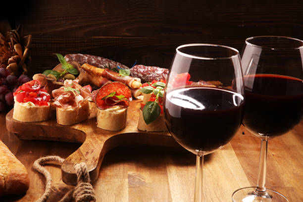 istock Traditional italian antipasto bruschetta appetizer with cherry tomatoes, cream cheese, basil leaves and balsamic vinegar on cutting board with prosciutto, salami, cheese 1148450687