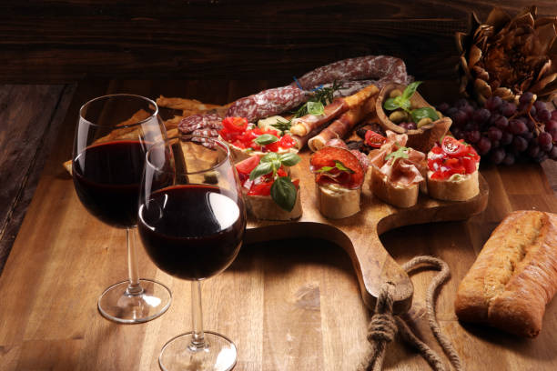 istock Traditional italian antipasto bruschetta appetizer with cherry tomatoes, cream cheese, basil leaves and balsamic vinegar on cutting board with prosciutto, salami, cheese 1148453740