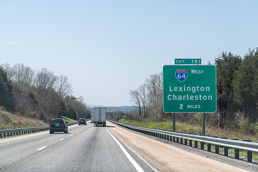 Lexington, USA - April 18, 2018: Road sign above highway road of Interstate 64 West with direction to exit 191 in 2 mile to Charleston in Virginia with traffic cars and truck