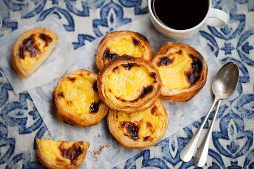 Egg tart, traditional Portuguese dessert, pastel de nata with coffee. Blue background.