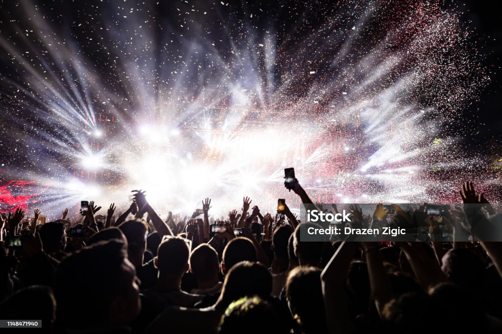 Confetti fireworks above the crowd on music festival. Excited audience watching confetti fireworks and having fun on music festival at night. Copy space. Music Festival Stock Photo