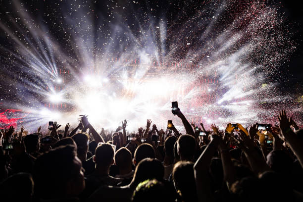Confetti fireworks above the crowd on music festival. Excited audience watching confetti fireworks and having fun on music festival at night. Copy space. stage performance space photos stock pictures, royalty-free photos & images