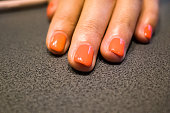Orange manicure. Female hand lies on the table