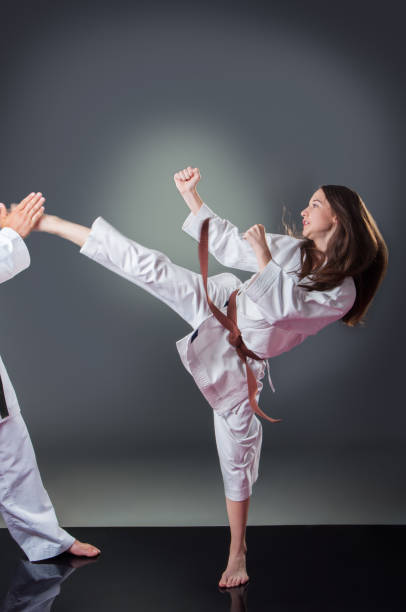 istock Beautiful young female karate player doing kick on the gray background 1148490518