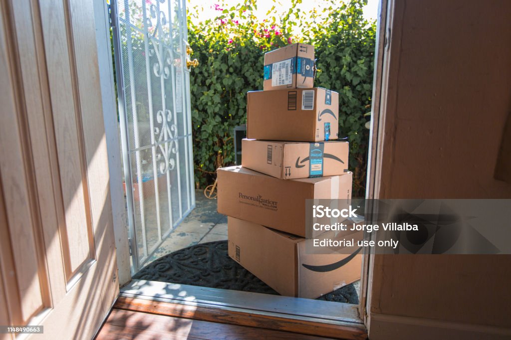 Cardboard package delivery at front door Los Angeles CA, November 11/22/2017: Image of an Amazon packages. Amazon is an online company and is the largest retailer in the world. Cardboard package delivery at front door during the holiday season. shipping package parcel box on wooden floor with protection paper inside. Amazon.com went online in 1995 and is now the largest online retailer in the world. Amazon.com Stock Photo
