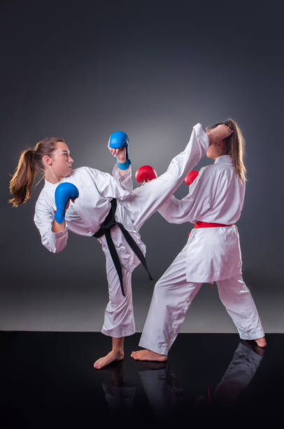 istock Beautiful young female karate player doing kick on the gray background 1148491563