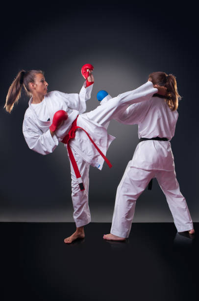 istock Beautiful young female karate player doing kick on the gray background 1148491565