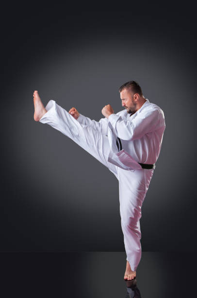 istock Handsome male karate player doing kick on the gray background 1148491944