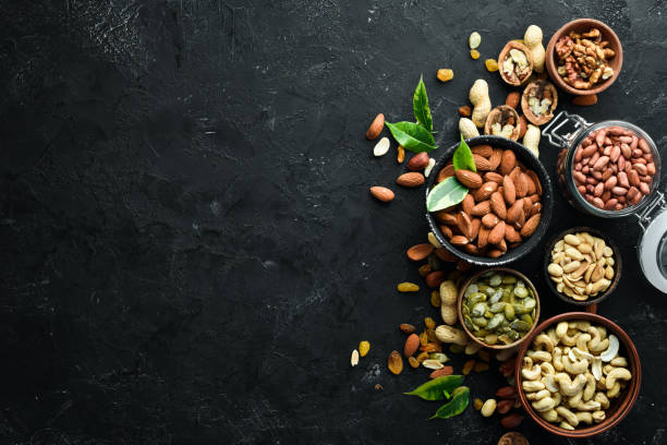 istock Assorted nuts on the old black background. Top view. Free space for your text. 1148494248