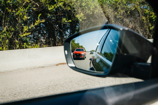 France - 19 Apr 2019: New red Hyundai Tucson SUV reflection in car rear view into driving fast on French highway