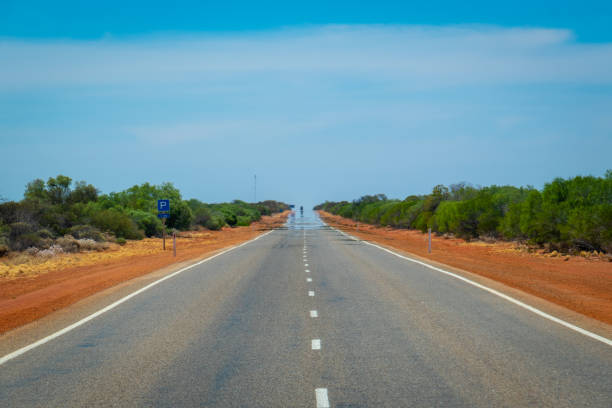miragem em uma estrada reta infinita que conduz com o australiano bush - arid climate asphalt barren blue - fotografias e filmes do acervo