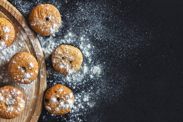 istock Homemade cupcakes with sugar powder on a black background. Selective focus, top view, copy space. 1148498318