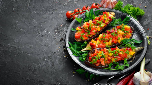 istock Eggplants baked with vegetables on a black plate. Top view. Free space for your text. 1148498725