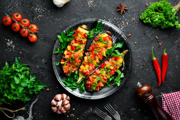 istock Eggplants baked with vegetables on a black plate. Top view. Free space for your text. 1148502707
