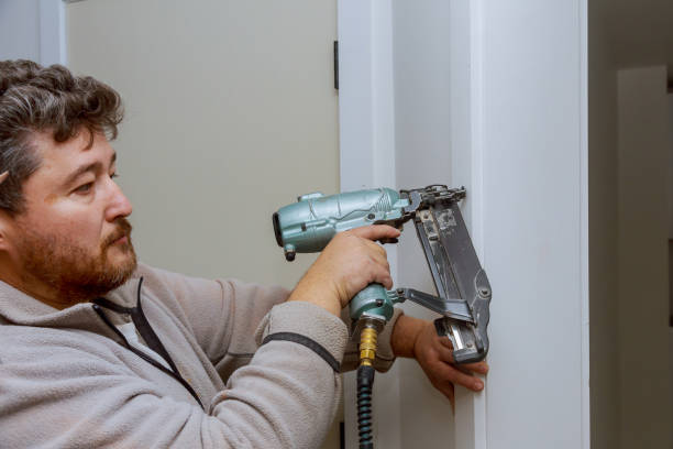 istock Carpenter using nail gun to moldings on door, framing trim, 1148508397