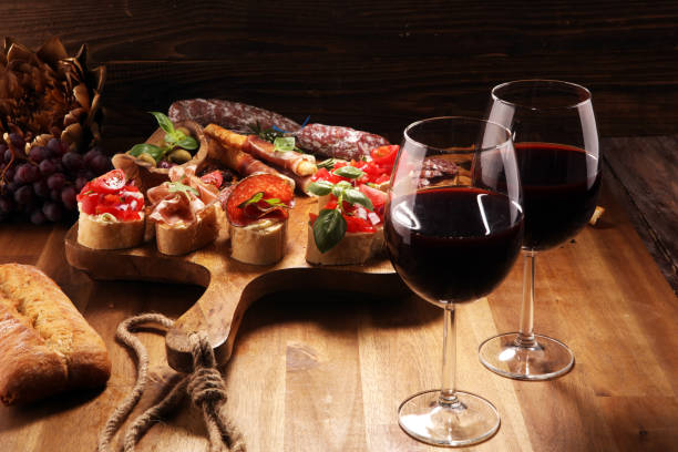 istock Traditional italian antipasto bruschetta appetizer with cherry tomatoes, cream cheese, basil leaves and balsamic vinegar on cutting board with prosciutto, salami, cheese 1148510028