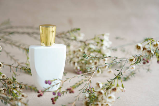 White parfume bottle with golden  in flowers