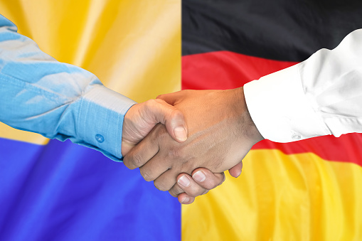 Business handshake on the background of two flags. Men handshake on the background of the Germany and Ukraine flag. Support concept