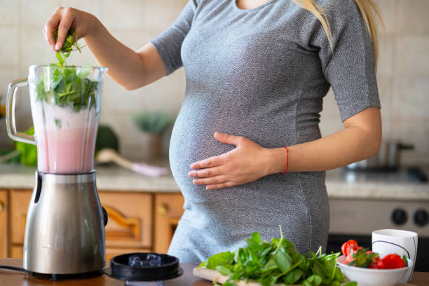 istock Pregnant woman preparing healthy drink at home, using blender 1148520485