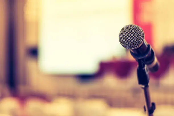 Photo of Microphone voice speaker in business seminar, speech presentation, town hall meeting, lecture hall or conference room in corporate or community event for host or public hearing