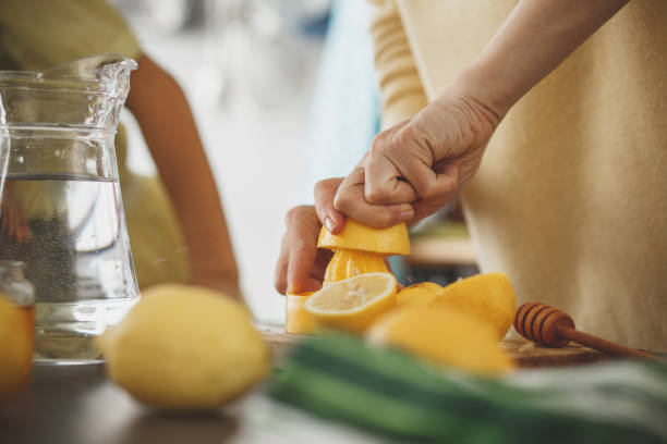 donna che stringe il limone al bancone della cucina - women juice drinking breakfast foto e immagini stock