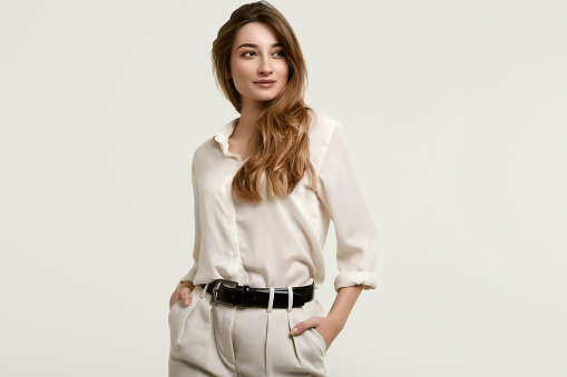 Portrait of gorgeous female brunette model posing in white fashion clothes in studio