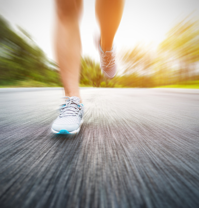 Woman legs running on asphalt road