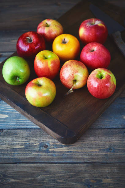 alimentación sana. tabla de cortar con un surtido de diferentes variedades de manzana - red delicious apple apple fruit vertical fotografías e imágenes de stock