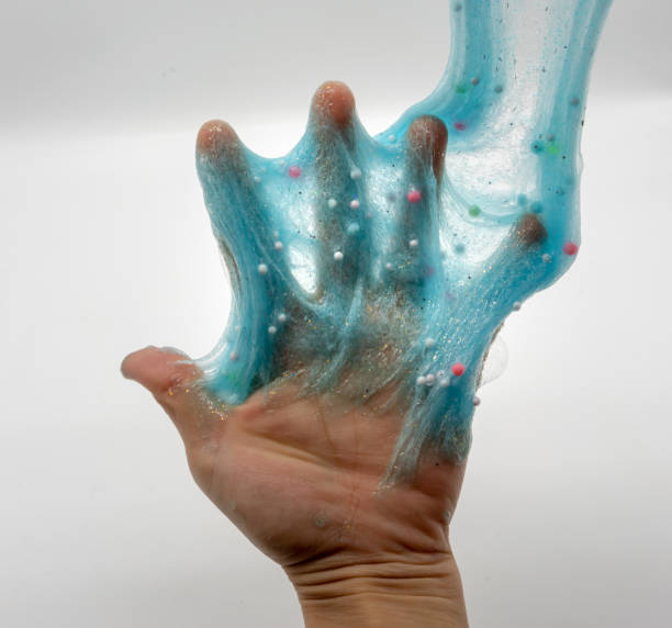 istock Hand playing or soaking transparent blue glitter slime isolated on white background 1148527119
