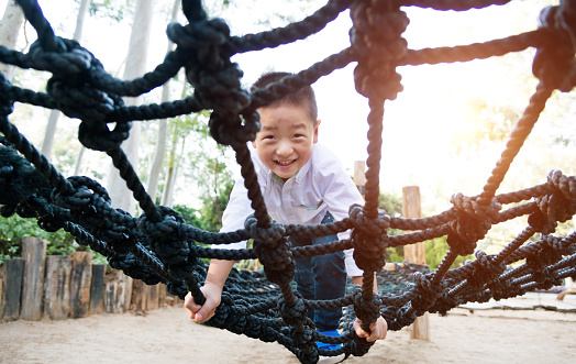 Little asian boy climbing rope frame