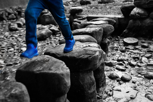 Little boy crossing stepping stones.