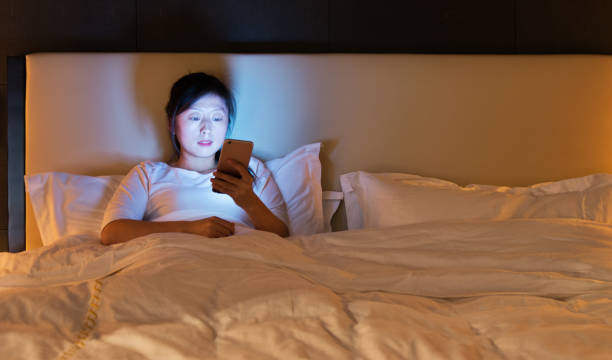 istock Young woman using a smart phone while in bed at night 1148528475