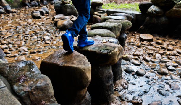 petit garçon traversant des pierres de progression - stepping stone stone stepping footpath photos et images de collection