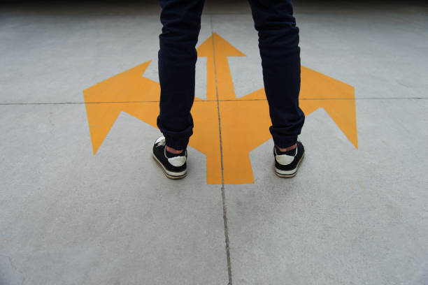istock Young man feet and three yellow arrows painted on floor 1148528495