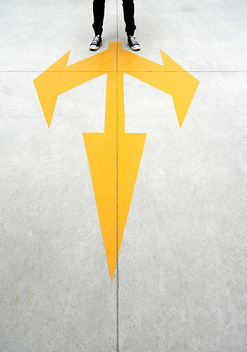 Young man feet and three yellow arrows painted on floor.