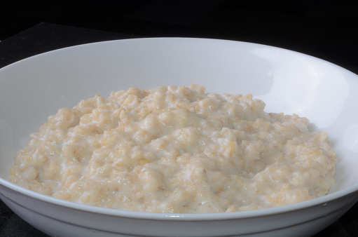 Healthy breakfast: homemade hot oatmeal porridge  served in a white bowl